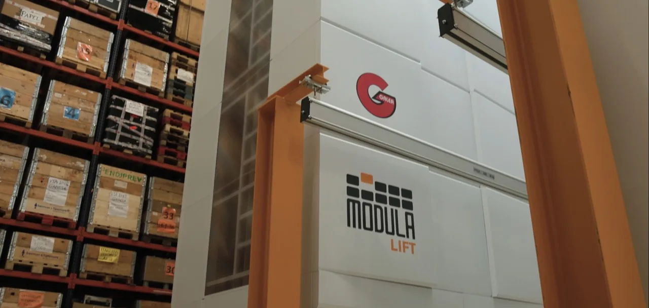 Almacén vertical Modula Lift instalado en Galea junto a estanterías con cajas de madera; fotografía de la ficha oficial del caso