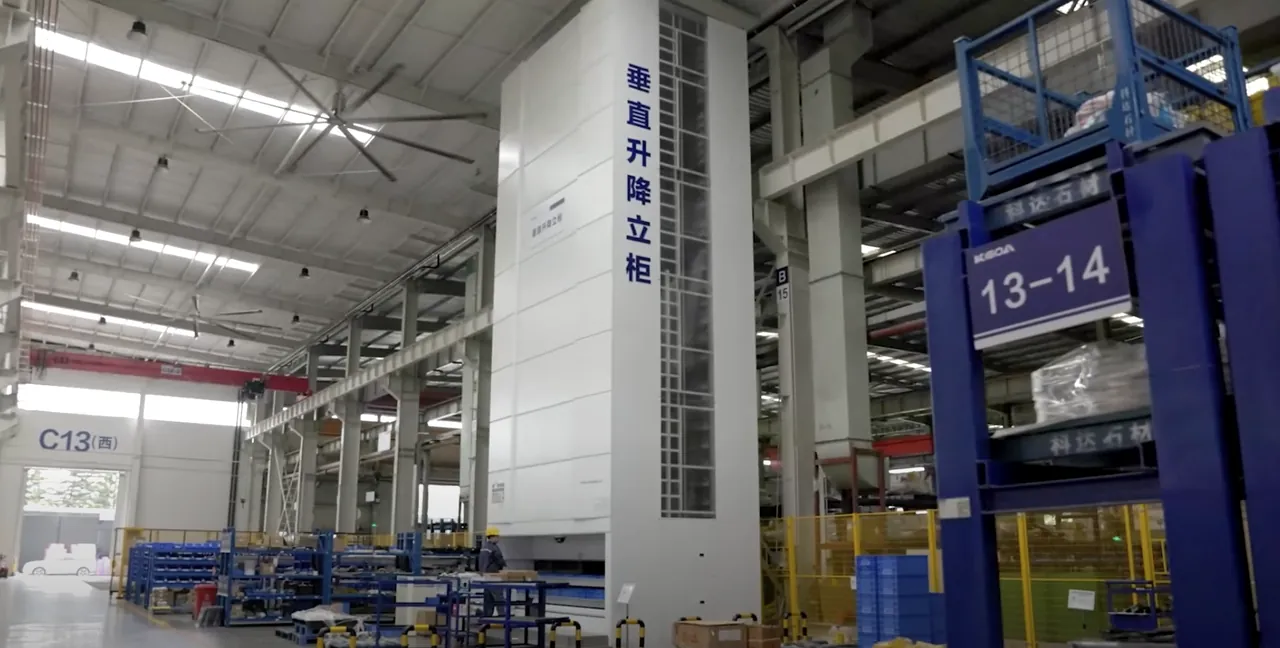 Almacén vertical Modula Lift de altura completa instalado en la nave de Keda, junto a estanterías con contenedores; fotografía de la ficha oficial del caso