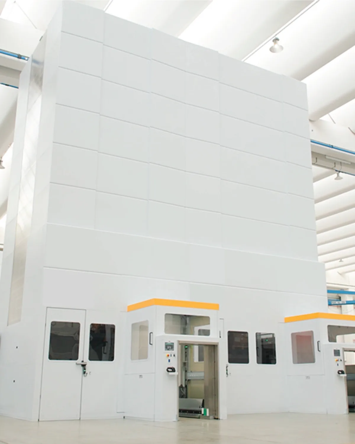 Almacén vertical Modula de altura completa instalado en una nave industrial luminosa, con dos bahías de picking al frente